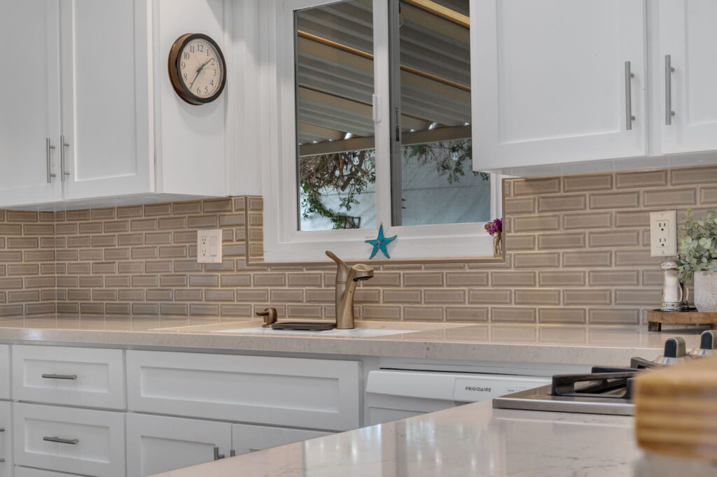 White kitchen with tan tile backsplash and garden window in San Diego