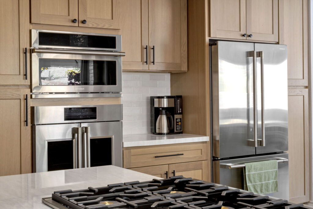 Light wood kitchen cabinets with built-in double oven and gas cooktop in San Diego