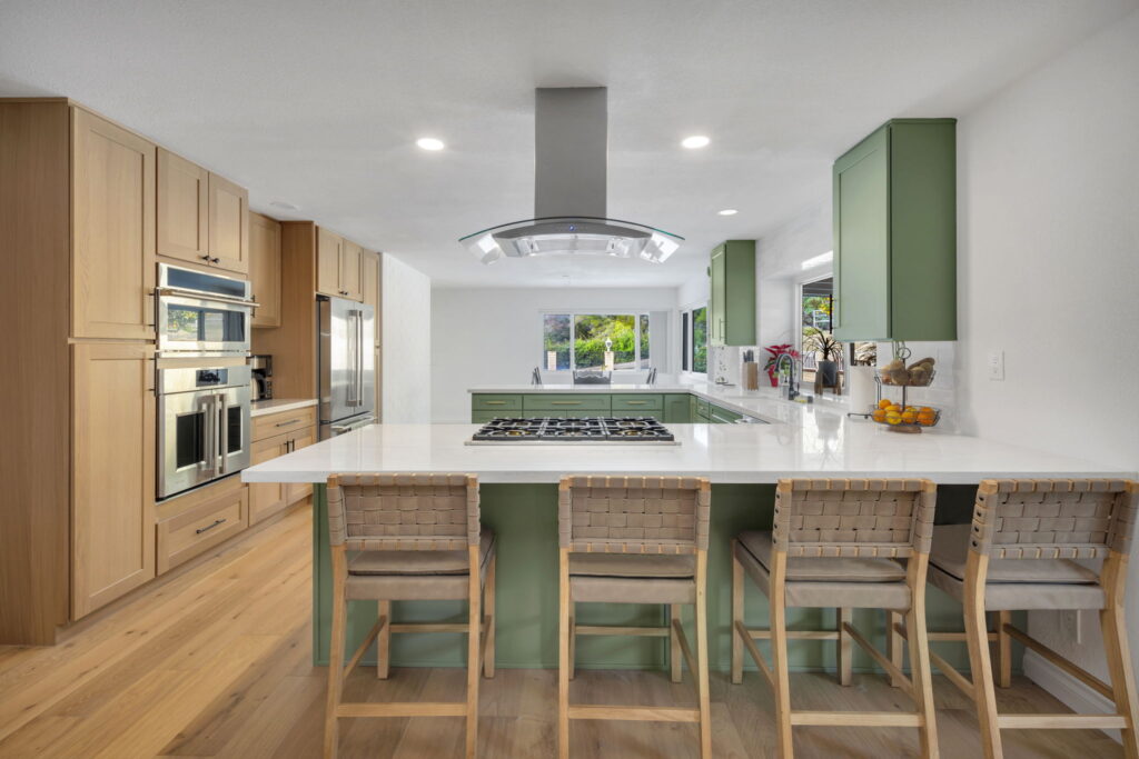 Kitchen remodel with light wood cabinetry, quartz island and woven bar stools in San Diego