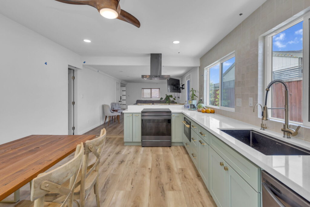 Oceanside kitchen remodel with sage green cabinets and butcher block peninsula