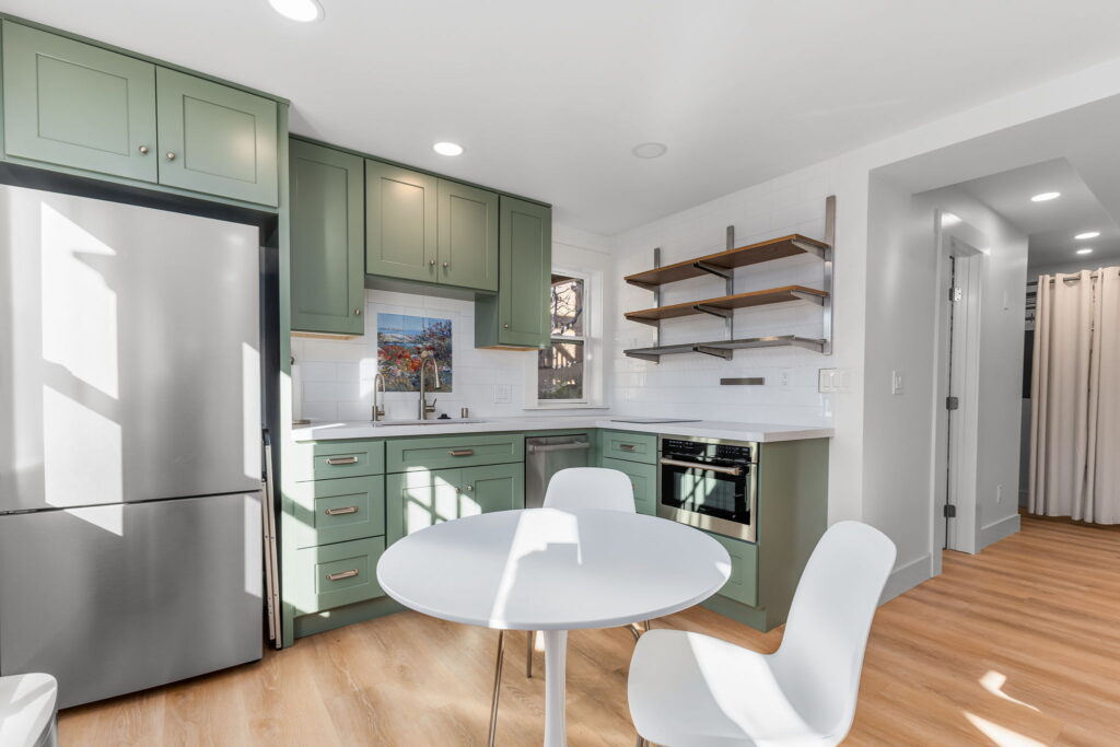 ADU kitchen with sage green cabinets and open shelving, garage conversion San Diego