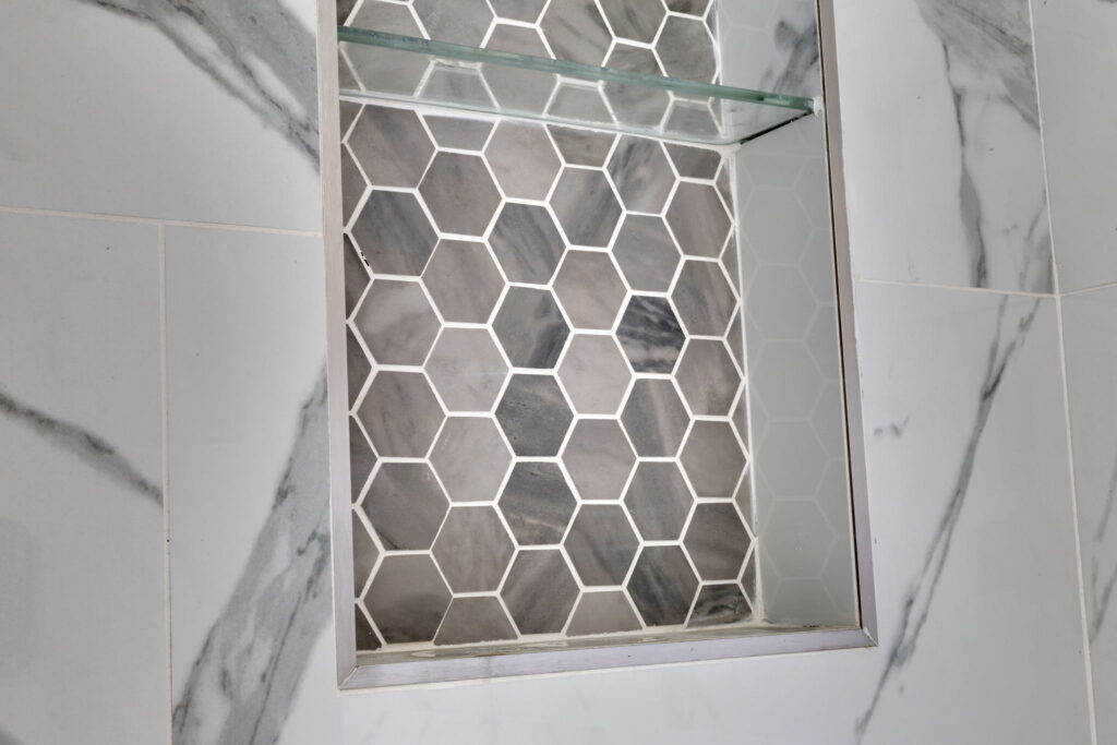 Marble shower with hexagon tile niche and glass shelving, La Jolla bathroom remodel