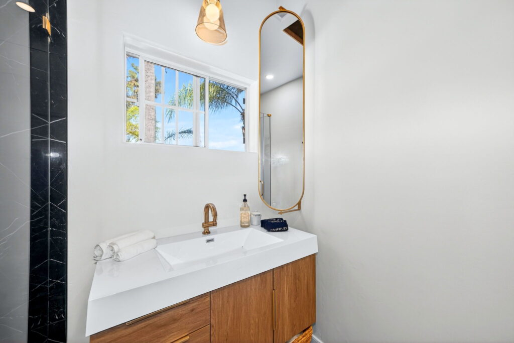 Bathroom renovation with floating walnut vanity and designer mirror in San Diego