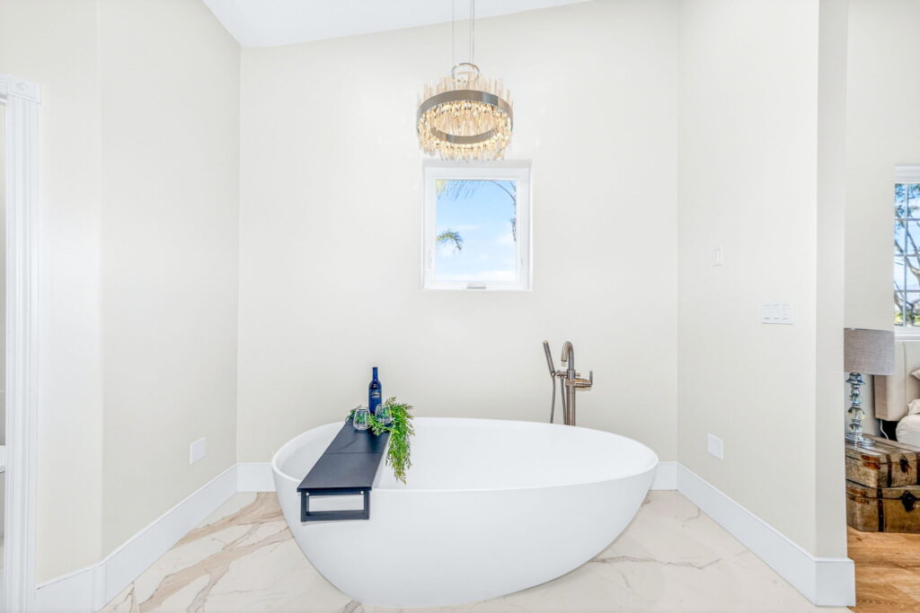 Master bathroom remodel with freestanding soaking tub and pendant chandelier by PBH Builders
