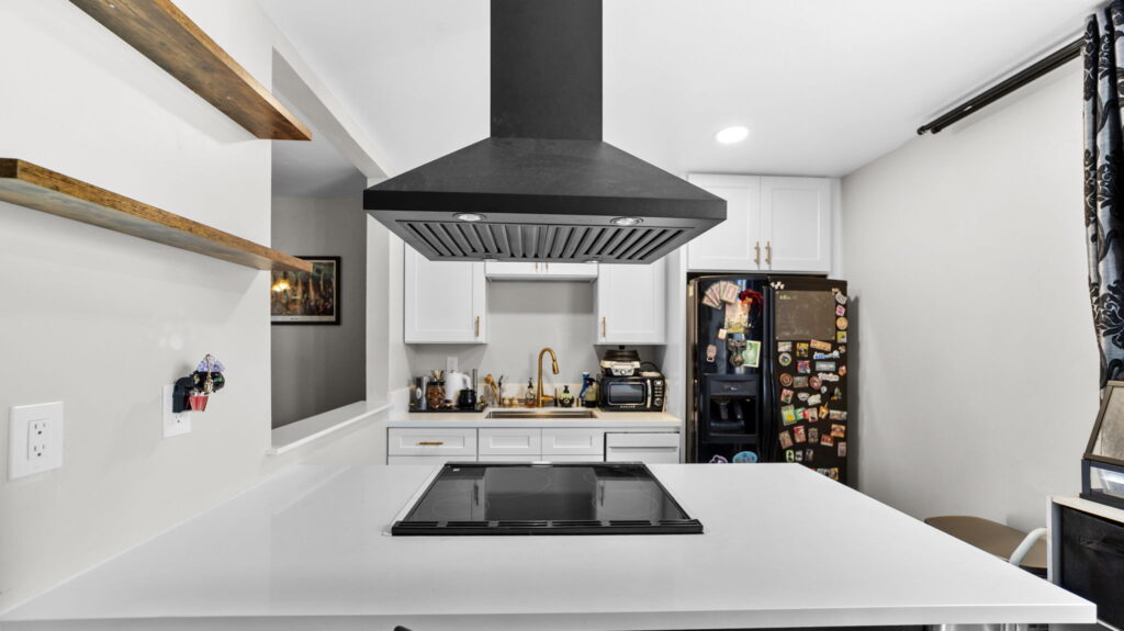 Two-tone kitchen remodel with black island, matte black range hood and gold fixtures in Chula Vista