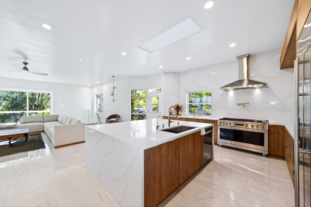 Open-concept kitchen remodel with quartz waterfall island and designer range hood by PBH Builders