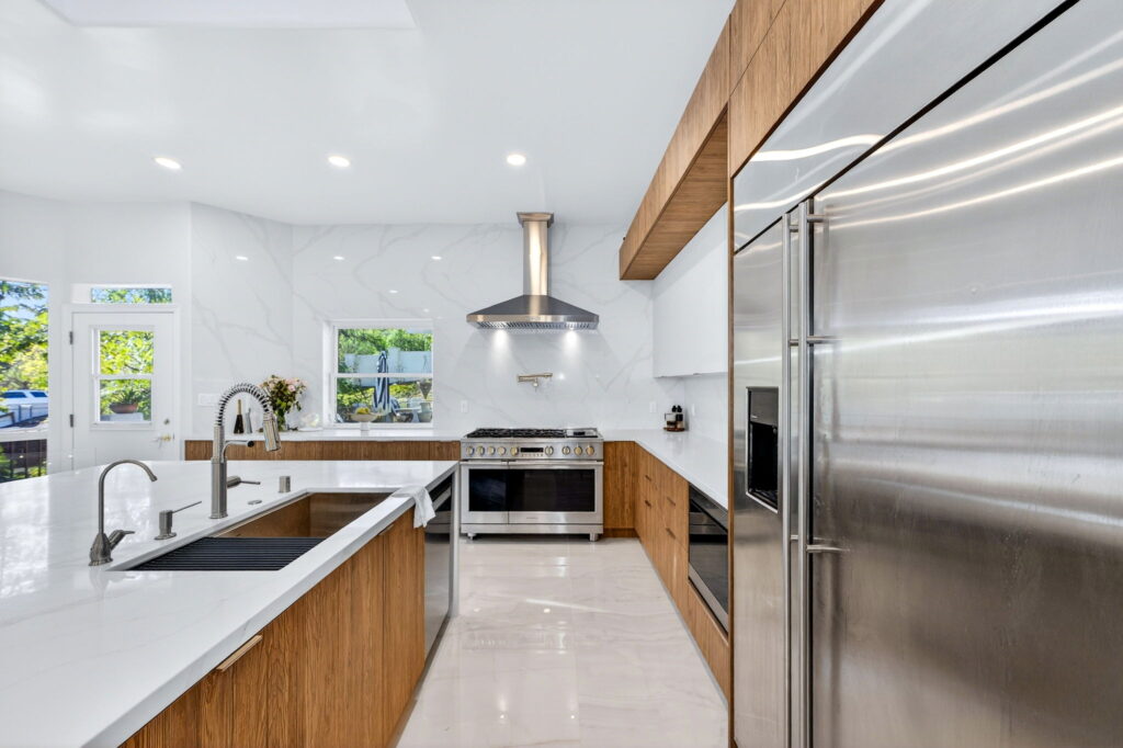 Modern kitchen remodel with exposed wood beam and built-in refrigerator by PBH Builders