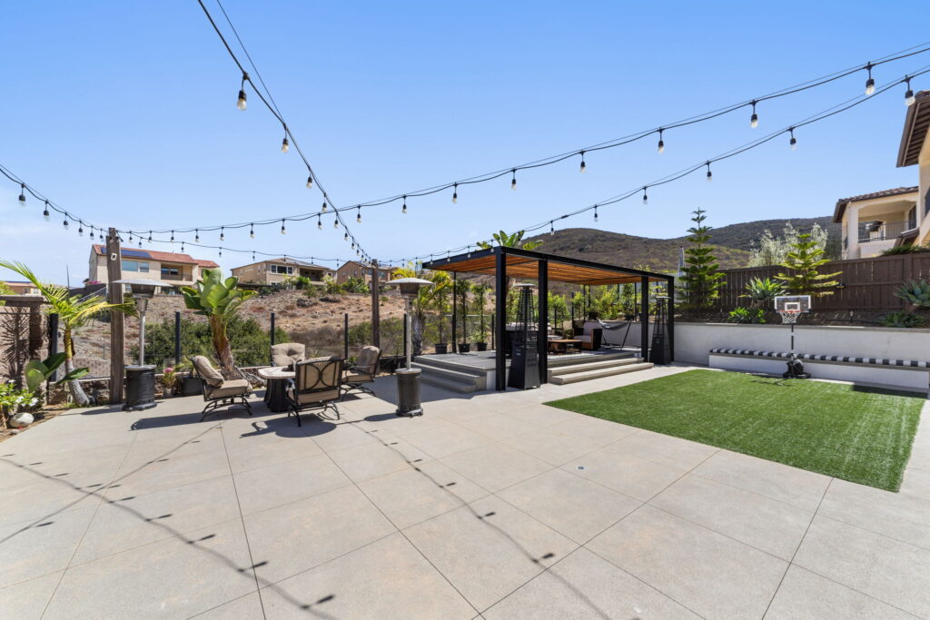 Backyard entertainment area with string lights, basketball court and pergola in San Diego
